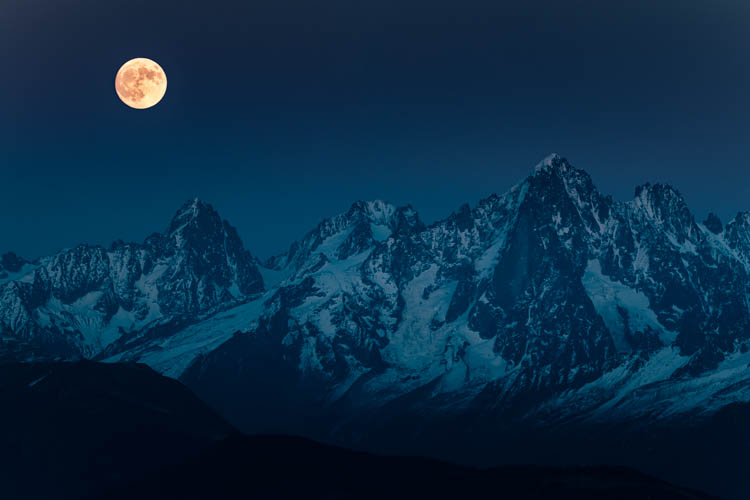 La pleine lune orangée surveille les sommets au Nord du Massif du Mont Blanc , France.